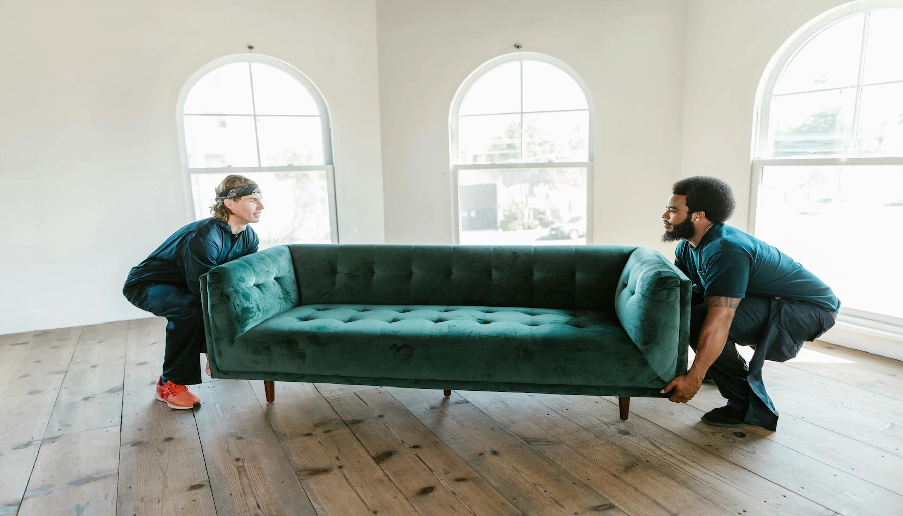 Two men in Saskatoon carrying a green couch in a home in Saskatoon.